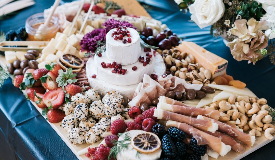 A massive charcuterie board is packed with sliced meats, cheeses, and fruit.