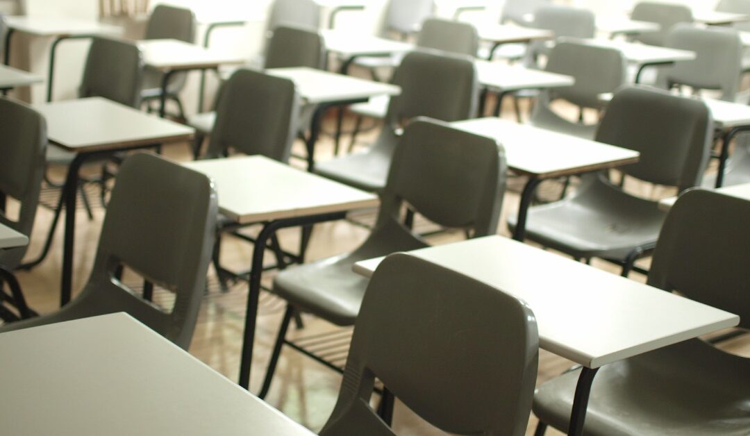 Moody light shines in classroom full of empty school desks.